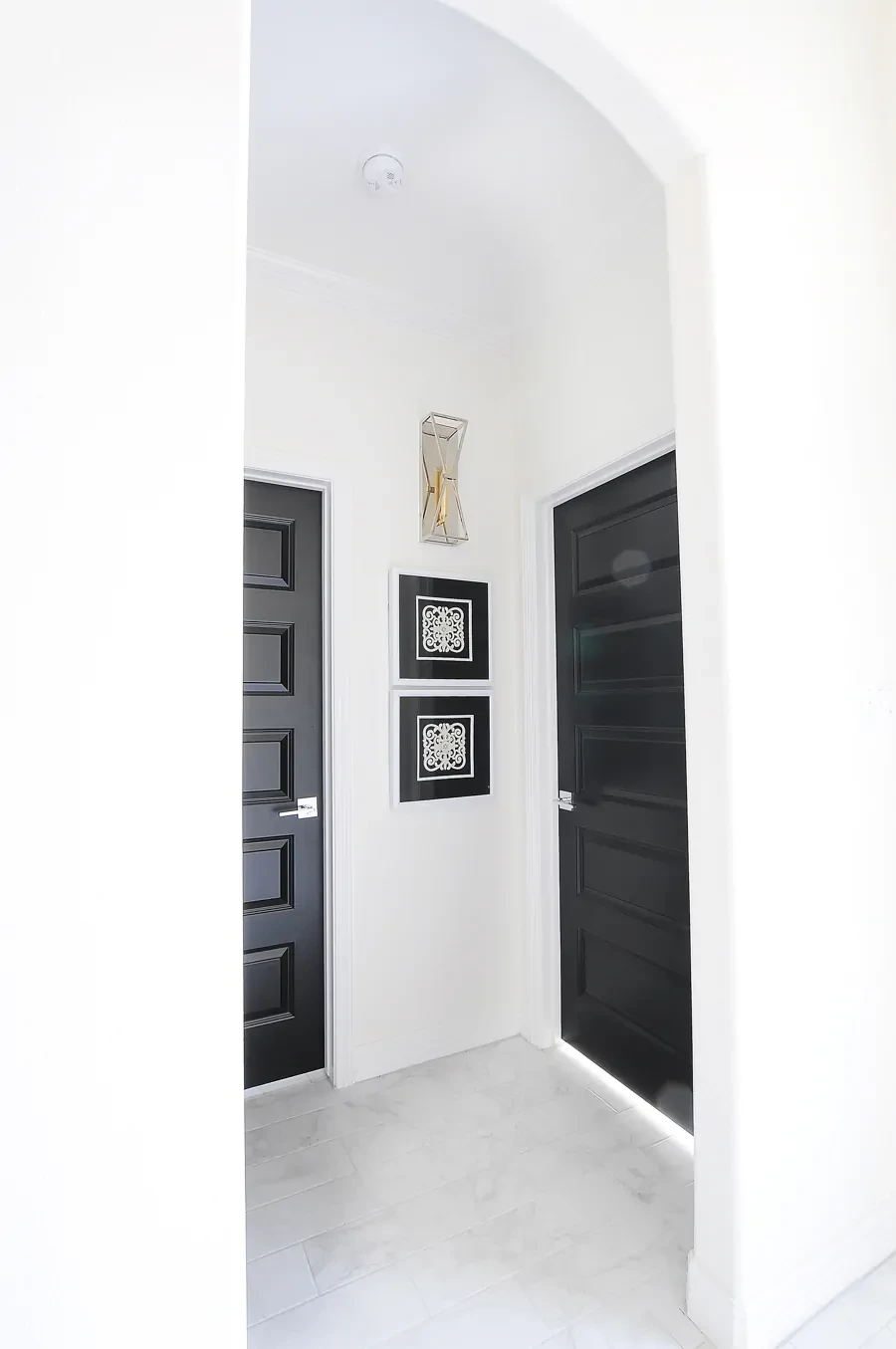 Black doors in a hallway with white walls and arches
